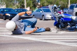 A motorcycle rider lying on the road after an accident.