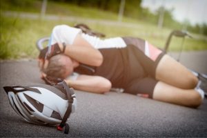 Cyclist lying on the side of the road after being injured from an accident.