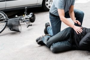 A man assessing a cyclist after hit by a car in Windsor.